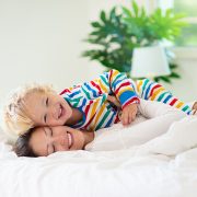 Mother and child playing in bed with clean white egyptian cotton sheets