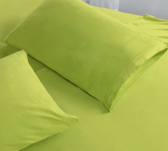 Spring green jersey cotton sheets on bed with two pillows