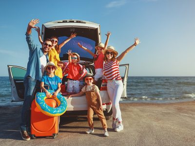 family at the beach waving from the back of their SUV with beach accessories