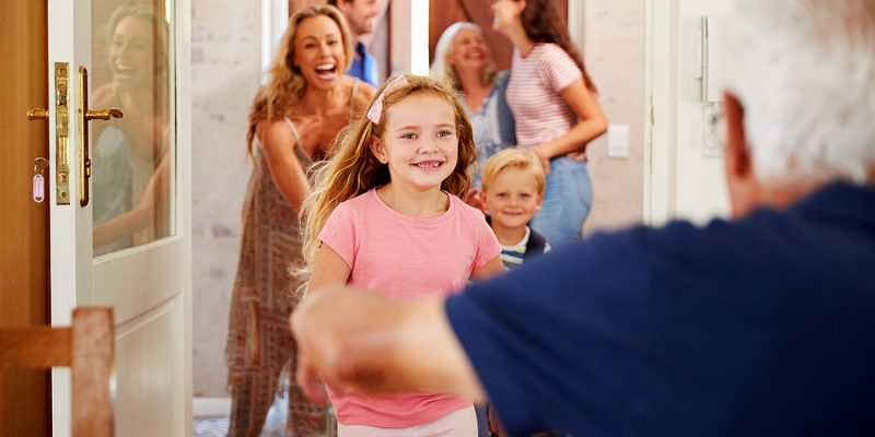 Happy grandparents greet arriving family with grandkids at family reunion for overnight visit as houseguests