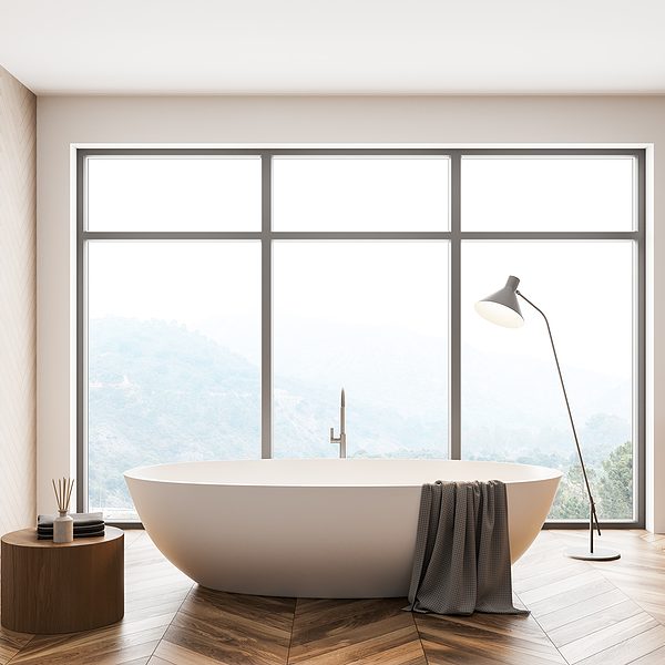 minimalist high end bathroom with white tub, gray bath towel, large windows and foggy mountain view
