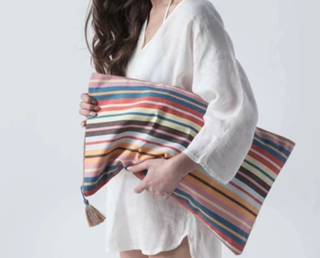 Girl in casual cotton shirt holding eco friendly pillow size cotton striped beach bag