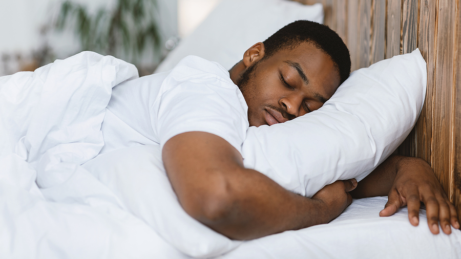 man sleeping on his stomach hugging pillow looking comfortable