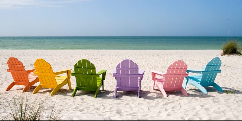 summer beach calm ocean view with six colorful wooden beach chairs