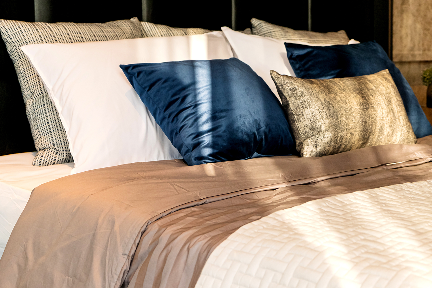 blue, gold, striped and white decorative pillows on hotel bed
