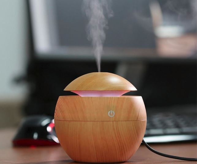 Round light wood diffuser and humidifier with cool steam on a computer desk