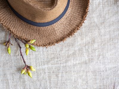 Top view of Summer brown panama straw hat with flower plant on organic linen