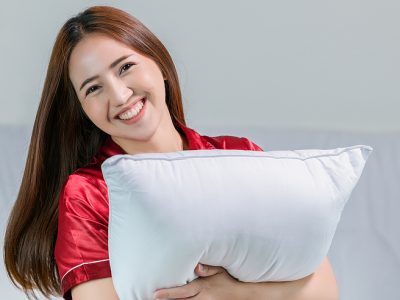 happy young woman hugging her fluffy comfortable pillow