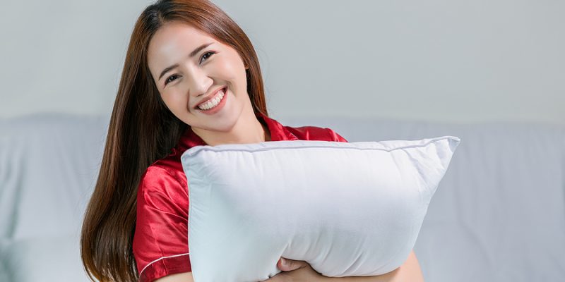 happy young woman hugging her fluffy comfortable pillow