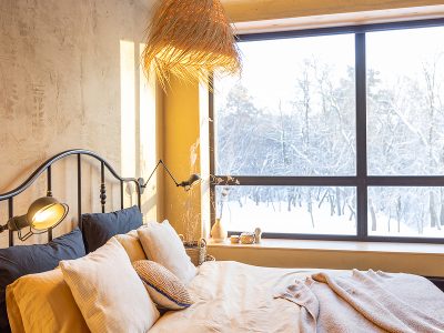 Stylish bedroom interior in winter with snow outside natural boho style