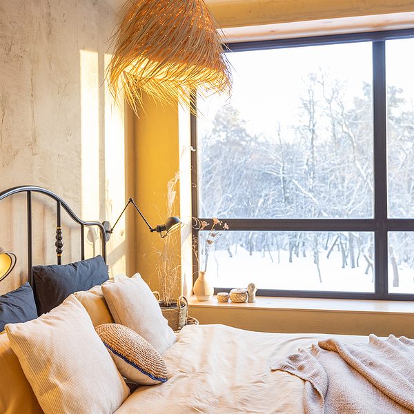 Stylish bedroom interior in winter with snow outside natural boho style