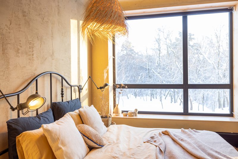Stylish bedroom interior in winter with snow outside natural boho style