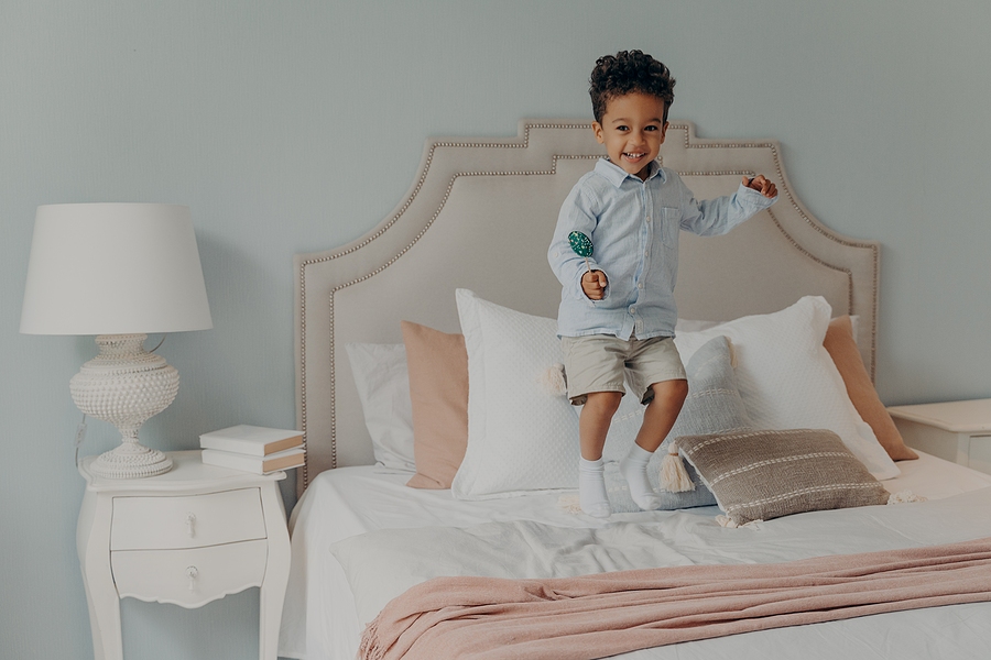 Boy jumping on good thread count bedding and linens