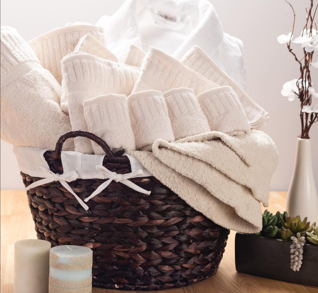 Photo of basket stuffed with cream colored cotton face wash cloths and towels